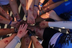 A group of people with the BoStrong "Red Hand" logo painted on their arms